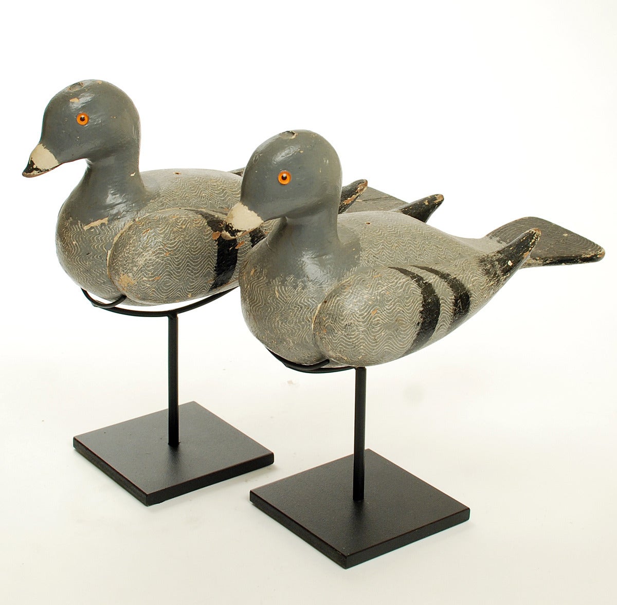 A pair of rare early 20th century pigeon decoys - circa 1900. hand carved and polychrome painted wood with inset glass eyes. Each decoy displayed on a high quality custom made stand. 

Dimensions: each decoy measures approximately 11 inches long x