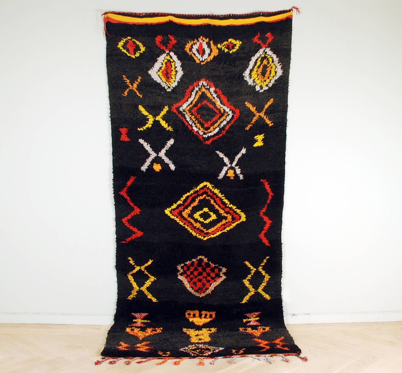 A large and impressive vintage Moroccan Berber Middle Atlas pile rug with colorful concentric diamonds and architectural motifs surrounded by a black ground and terminating into hand woven kilim ends and fringe. In overall excellent, original
