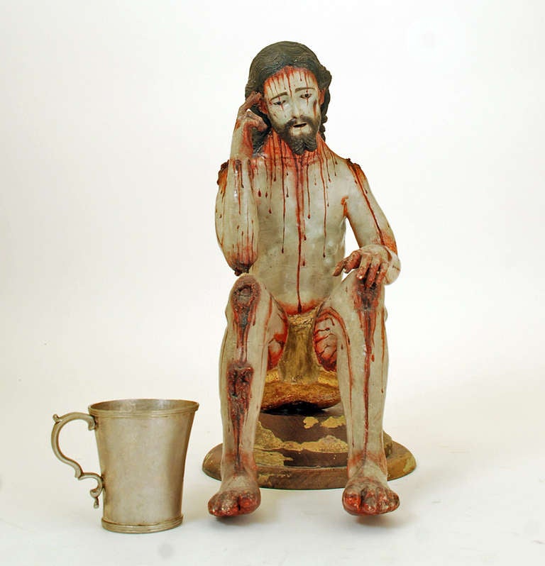 This rare 18th century Spanish colonial figure represents The Flagellation of Jesus Christ. Hand-carved and polychrome painted wood with inset glass eyes. Seated on the original platform base. Silver cup is shown for scale only and is not part of
