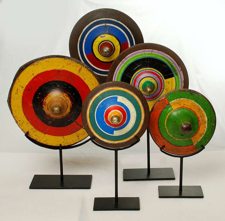 A collection of five vintage Gangsing spinning tops - each with colorful hand painted patterns and steel ring. Used in men's competitions by the Sasak People in Lombok Villages - Indonesia. Circa 1950's / 1960's. Each displayed on a high quality