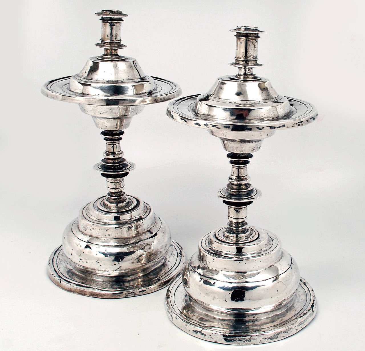 A pair of magnificent 17th / early 18th century Spanish Colonial devotional silver candlesticks with large footed ring base, baluster form stem, multiple node rings and a large node ring drip pan surmounted by a socket. The underside with original