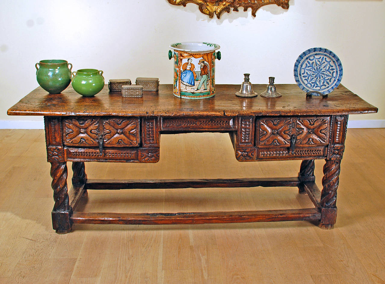 Outstanding late 17th century Spanish Baroque period chestnut kneehole desk with large single plank top over two large hand-carved drawers and barley twist legs all connected by a perimeter stretcher base. Carved on all sides. With excellent wear