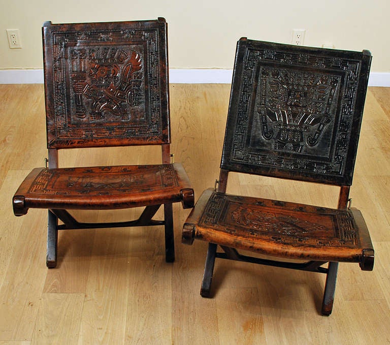 A pair of rare mid century Mexican Campeche chairs in rosewood with beautiful hand tooled and embossed leather Azteca motifs - each with folding wood frames.

Dimensions: 28 inches high x 22 inches wide.

In excellent, original condition. Sturdy