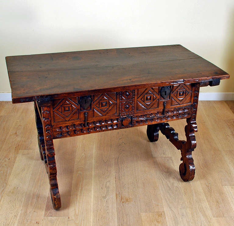 A very fine and rare early 18th century Spanish Baroque period walnut table (circa 1720) with thick rectangular top over two deeply carved drawers with original heart shaped lock-plates, all resting on scroll carved legs. Two hidden compartments are