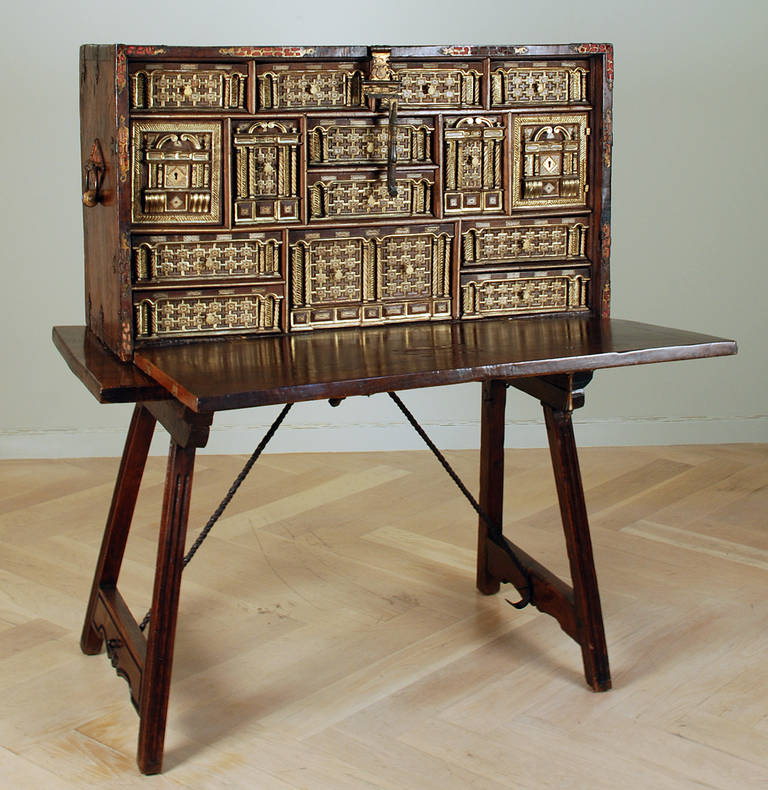 A stunning late 16th century Spanish walnut drop front bargueño with elaborate iron hardware mounted over fine English silk. The interior with fifteen gilt-wood compartments, all with elaborate carving, ornate detail and original iron drawer pulls.