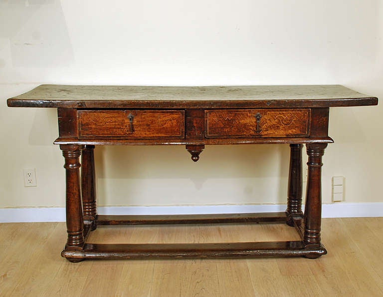 A fine 17th century Italian baroque period walnut library table with a single plank top over two inlaid drawers and turned legs connected by a stretcher base. Verso also with fruitwood inlay. In excellent, original condition with lustrous surface