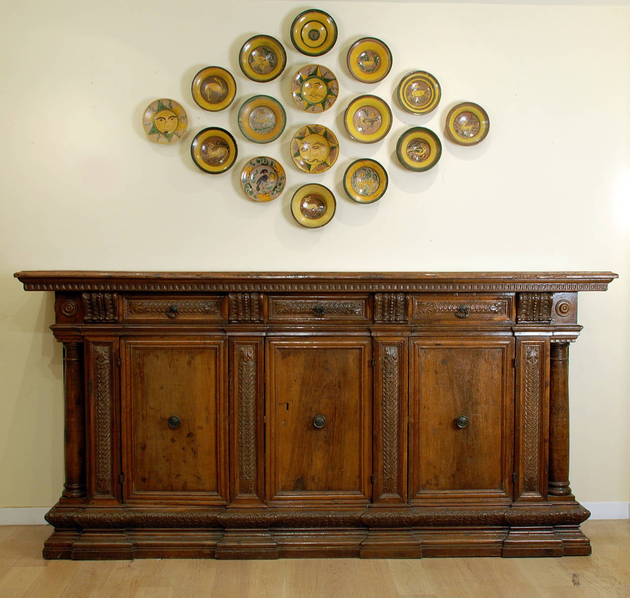 A monumental, one-of-a-kind, early 17th century Italian baroque period walnut credenza with a large rectangular top over a carved frieze with three large drawers separated by four smaller drawers. Main body with three paneled doors flanked by turned