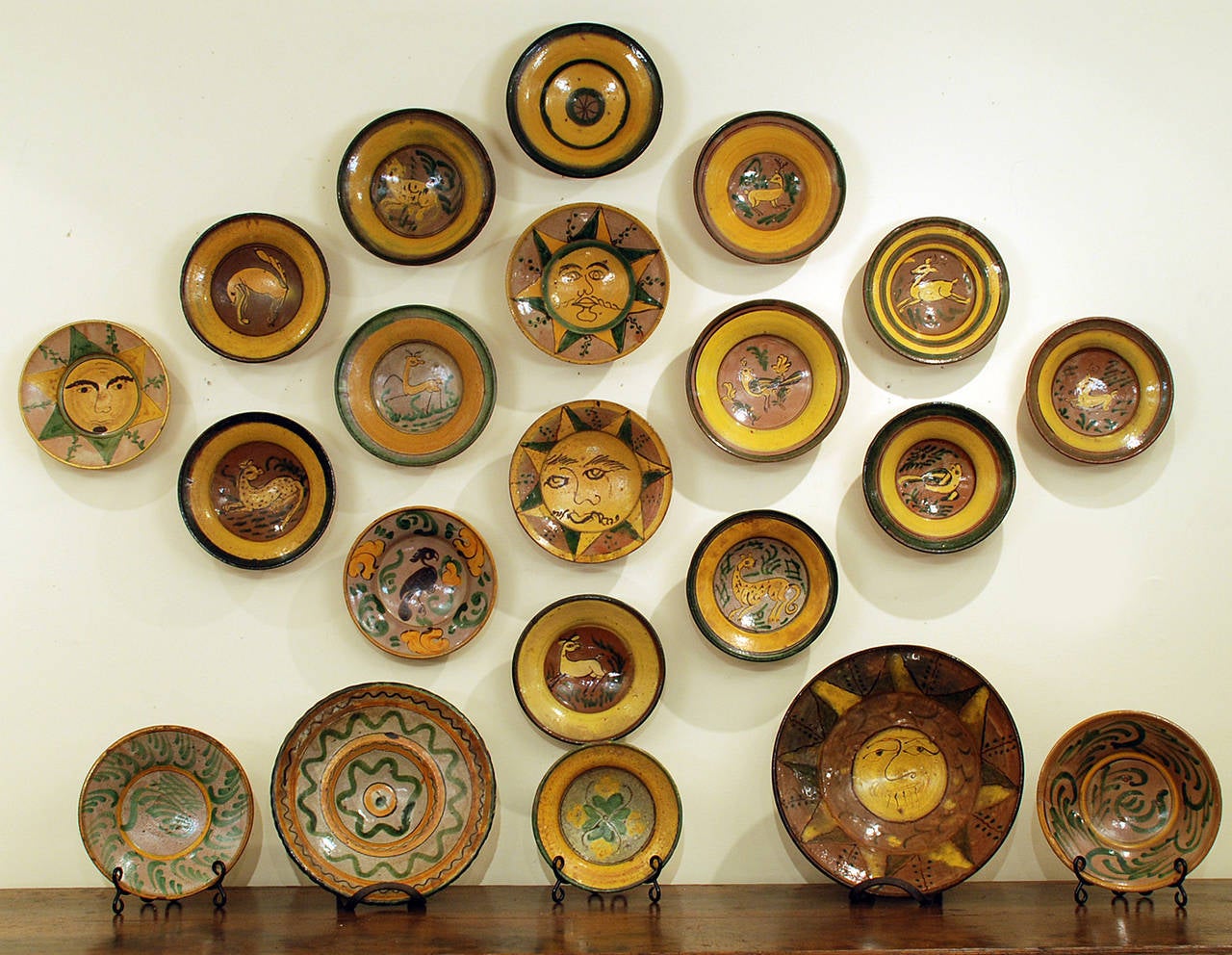 A collection of 21 hand selected late 19th and early 20th century yellow and green patterned Majolica plates, made by the Montiel Family Studio in Antigua, Guatemala. The collection includes several birds, deer, spotted leopards, jaguar and four