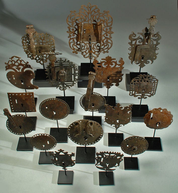 A collection of fine and rare 17th and 18th century Spanish colonial iron furniture escutcheons. 18 pieces total. Displayed on high quality custom made stands. <br />
<br />
Dimensions: largest measures 17 inches high with display stand or 12.5