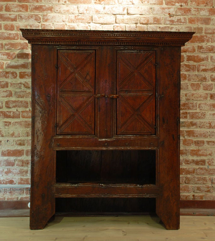 A fine 17th / early 18th century Spanish (Basque) two door walnut cabinet. The stepped dentil carved cornice above two panelled doors, a long drawer and an open shelf raised on rectangular supports.<br />
<br />
Dimensions: 62 inches high x 52