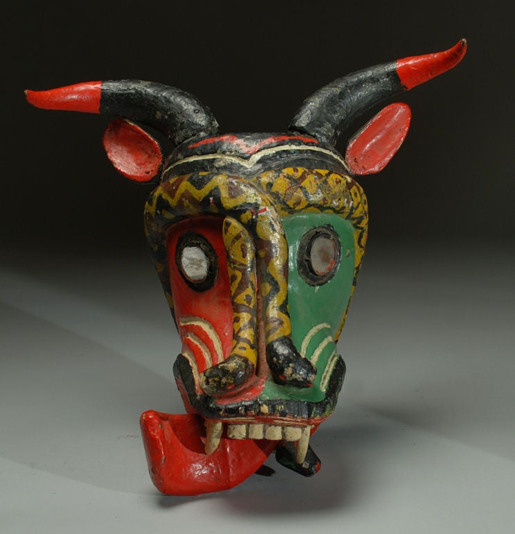 A large and impressive early 20th century Mexican bull devil mask with adjoining coral snakes, mirrored glass eyes, large wooden teeth and polychrome painted horns. Guerrero - circa 1930's / 1940's. The smaller mask is shown for scale only and is