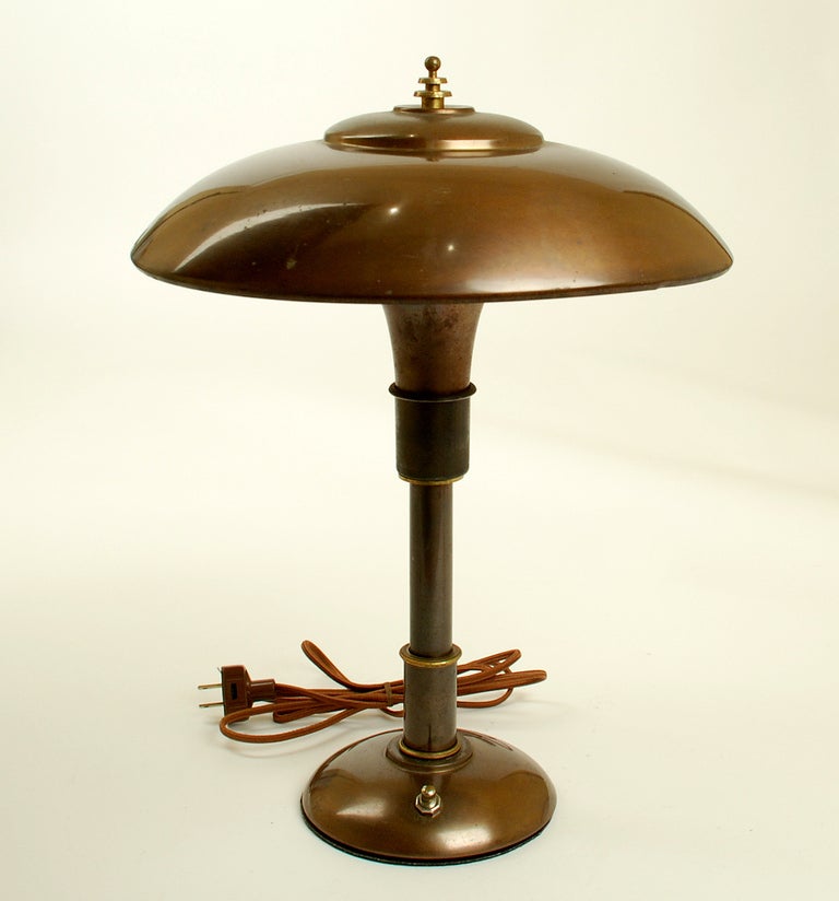 A Fine art Deco machine age 'Guardsman' brass table lamp made by the Faries Manufacturing Co., Decatur., IL and designed by Bert Dickerson. All original with original bronze finish. Professionally rewired. Circa 1937.

Dimensions: 18 inches x 14