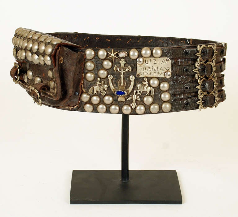 A superb early 20th century hand tooled leather gaucho belt from the Pampas in north-eastern Argentina. The belt is decorated all over in silver milagros with metal studs and a large pouch, all  fastened together with four silver mounted buckles.