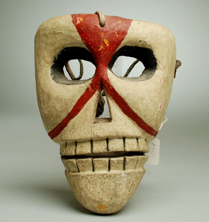 This rare early 20th century Mexican mask from Oaxaca, beautifully sculpted and painted in deep shades of burgundy over a creamy white slip, represents a 'calaca' -- a skull, used in ceremonial drama dances usually during Day of the Dead