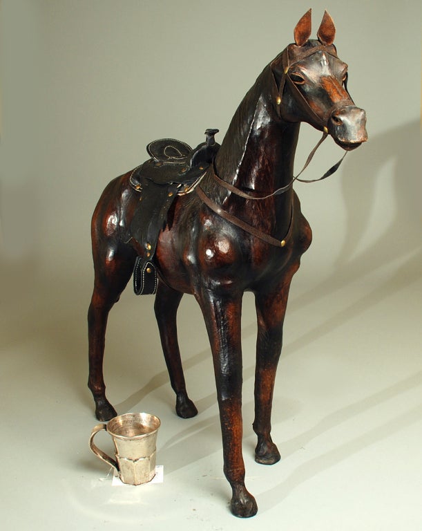 A wonderful early 20th century hand carved wooden horse from Mexico -- clad all over in supple leather with leather saddle, reigns and glass eyes. Mexico - circa 1930. The silver cup is shown for scale only and is not part of this listing.