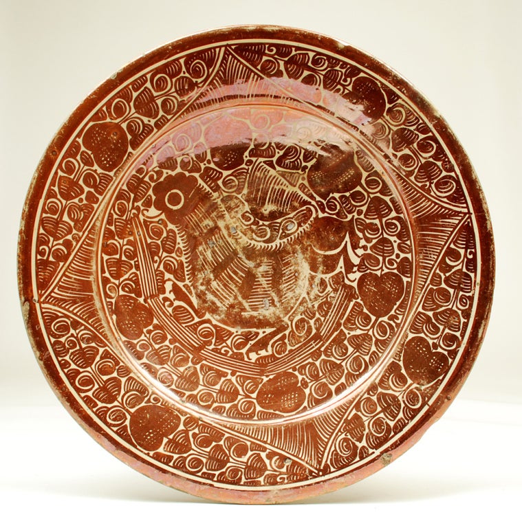 A stunning late 17th century Hispano Moresque Lusterware charger in deep copper over a milk white slip. Classic paralot bird motif surrounded by foliage and geometric patterns. Valencia, circa 1680 - 1700.

Dimensions: 14.75 inches diameter.

In