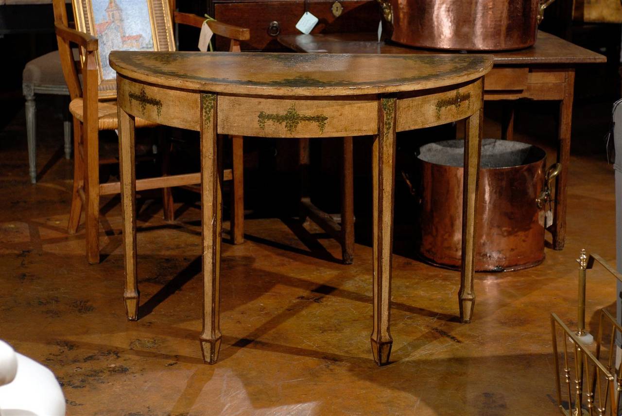 The top is decorated with a design of dark green vine leaves and tapered legs are set off by a dark border.  Each console is freestanding but the two may be placed together to form an attractive round center table.