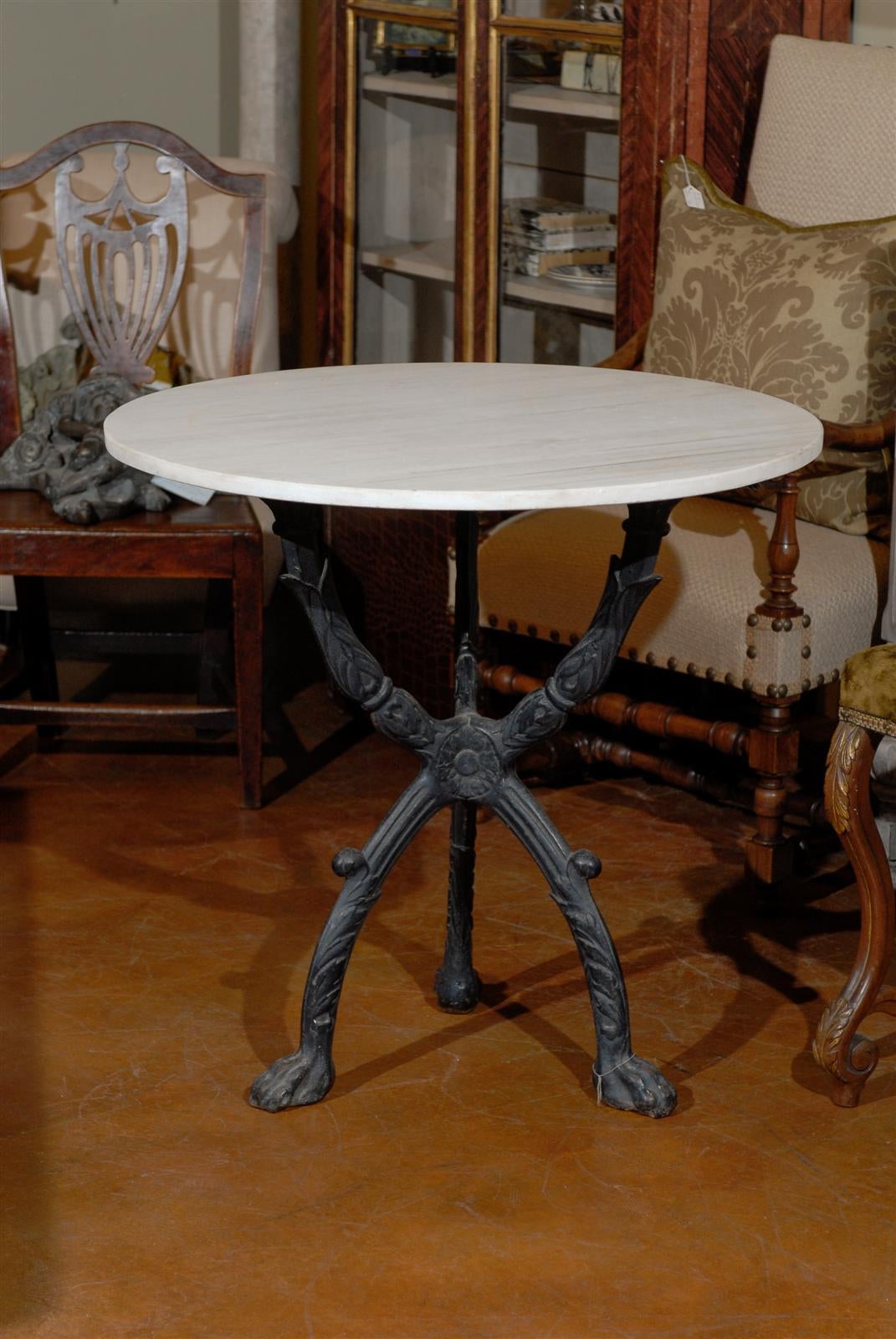 A French wrought-iron and marble top round bistro table with tripod base from the 19th century. This French bistro table features a circular white veined marble top, sitting above a wrought-iron tripod base. A perfect tribute to the French ironwork
