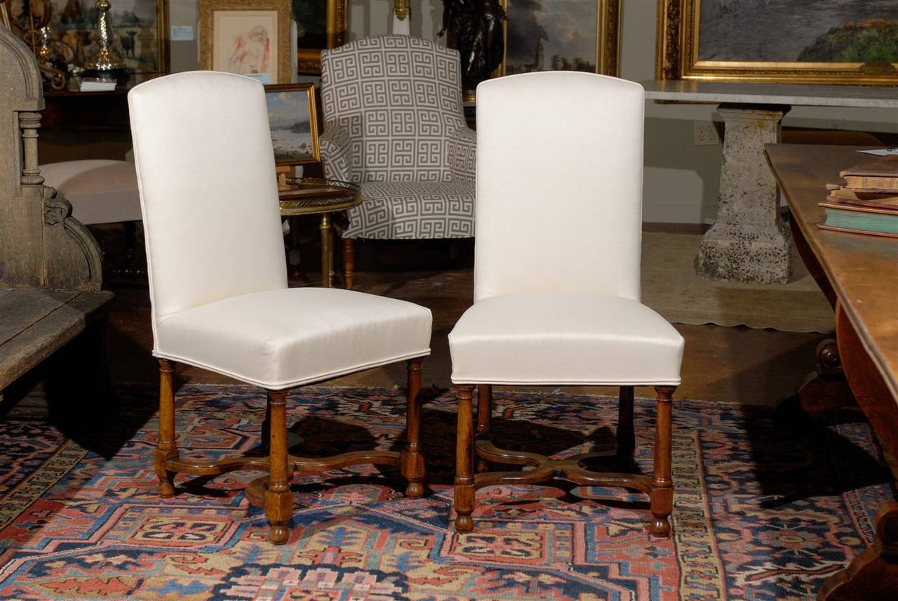 Set of eight Louis Philippe style walnut upholstered dining chairs, each with a shaped rectangular top surmounting a conforming seat raised on turned legs and joined by a curved X-form stretcher. 