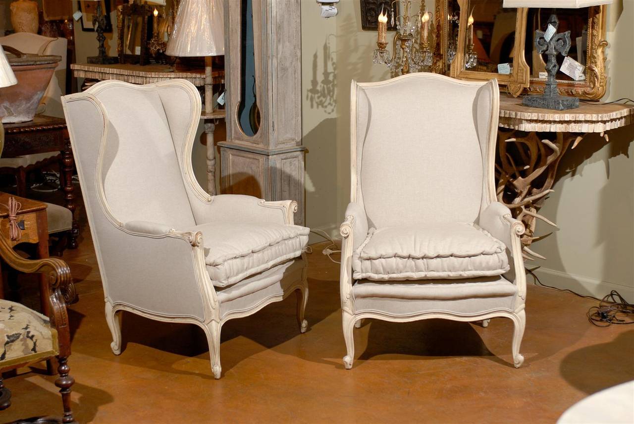 Pair of early 20th century Louis XV style paint decorated upholstered bergeres, each with a shaped rectangular back surmounting a conforming seat and raised on cabriole legs.