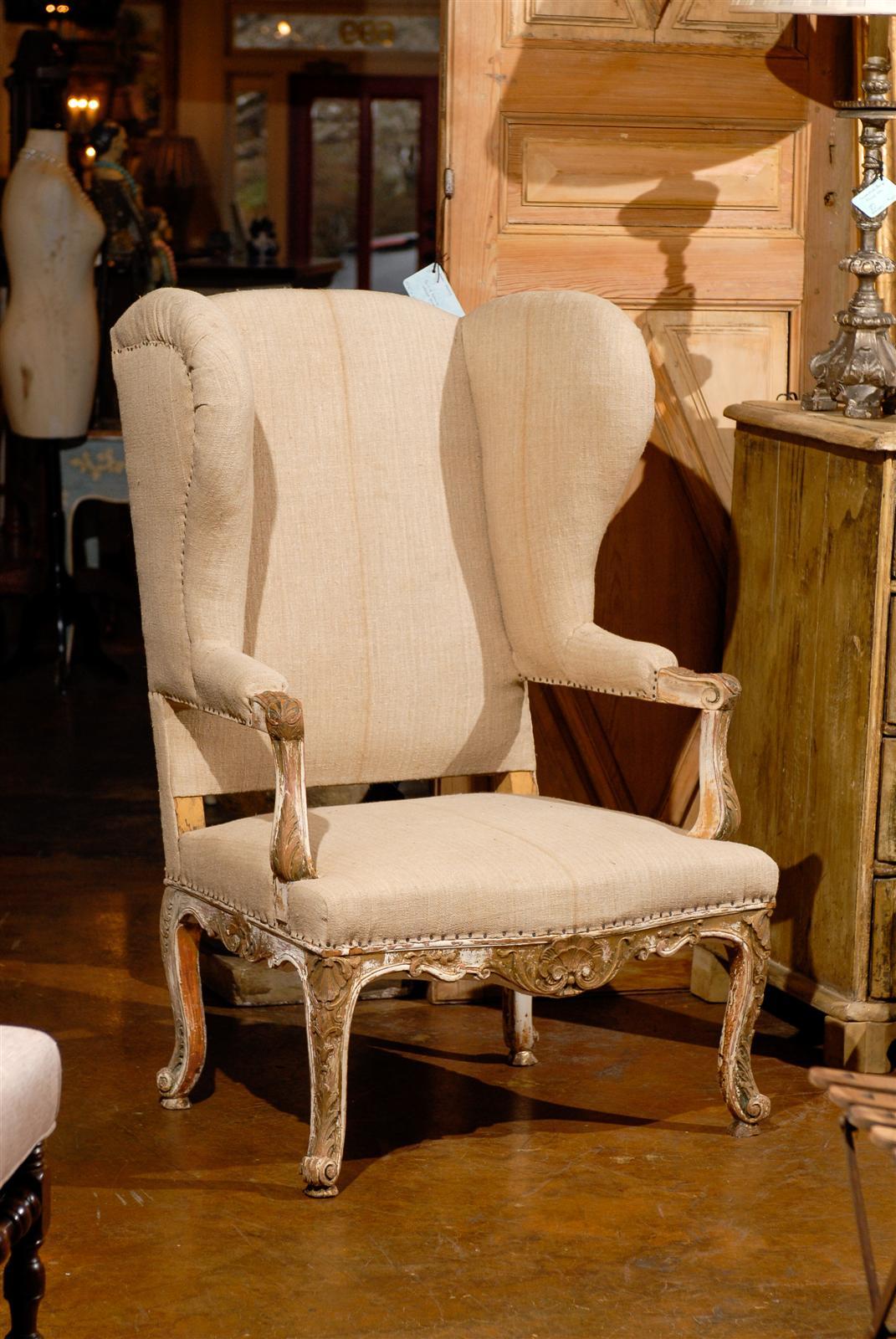 19th century French giltwood upholstered wing chair, the rectangular shaped back and elaborate wings surmounting a conforming seat, raised on cabriole legs, with nail trim throughout. 