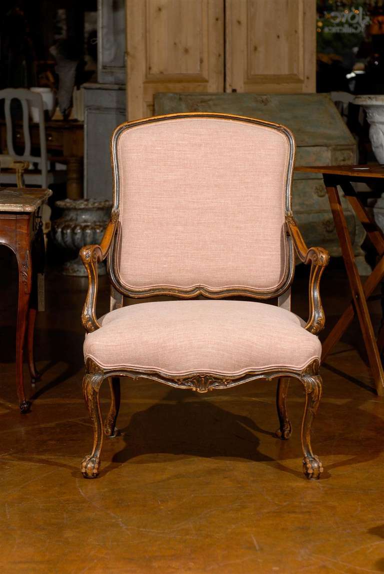 An Italian walnut Louis XV style fauteuil “à la Reine” with scrolled arms and cabriole legs from the 19th century. This Italian walnut armchair features a straight yet slanted back with scrolled arms, slightly reminiscent of the Louis XIV period in