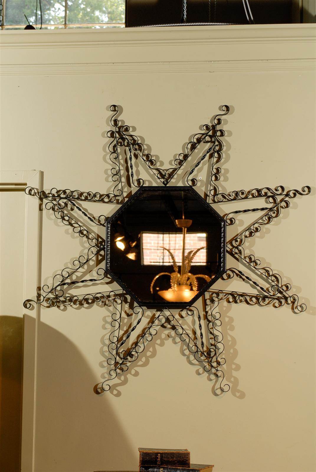 Vintage French octagonal mirror surrounded by scrolling metal in a star shape.