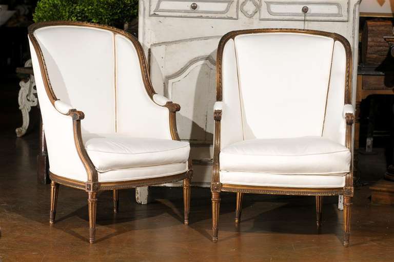 Pair of 19th century French upholstered bergeres, each with a full trapezoidal back and arms surmounting a conforming seat and raised on straight tapering fluted legs.