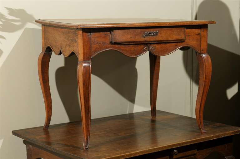 19th century French walnut table, the rectangular top surmounting a single drawer and curved apron, raised on splayed legs.