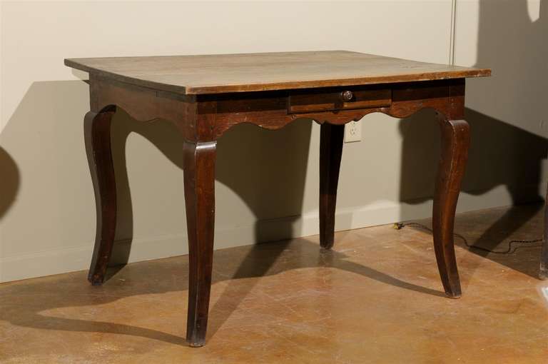19th century large walnut table or desk, the rectangular top surmounting a curved apron with a single drawer and raised on splayed legs.