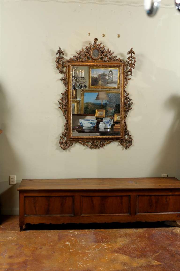 18th century giltwood Tuscan mirror, the triangular form crest with central design surmounting a rectangular mirror, with overall scrolling floriate and vine design.