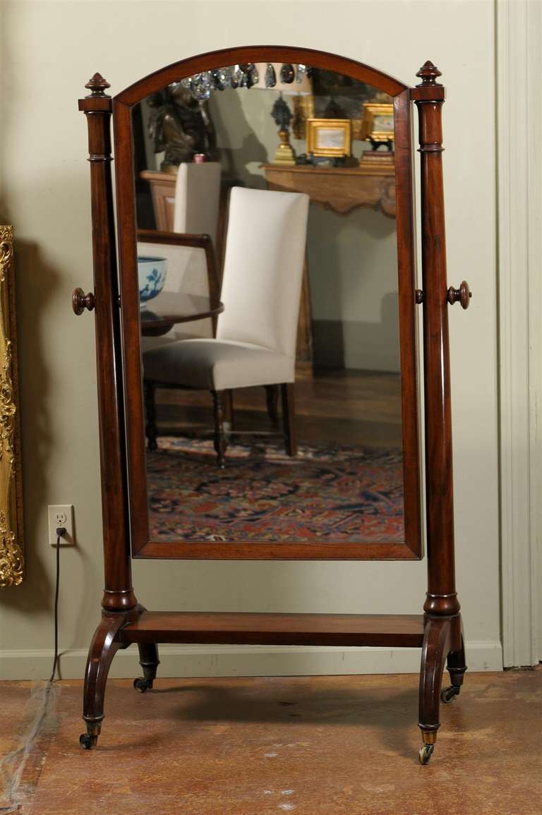 A Scottish mahogany free standing cheval mirror from the early 19th century. Born in Scotland circa 1820, this piece features a full length mirror, attached on the sides to a base, allowing the mirror to swivel at will. The two vertical supports are