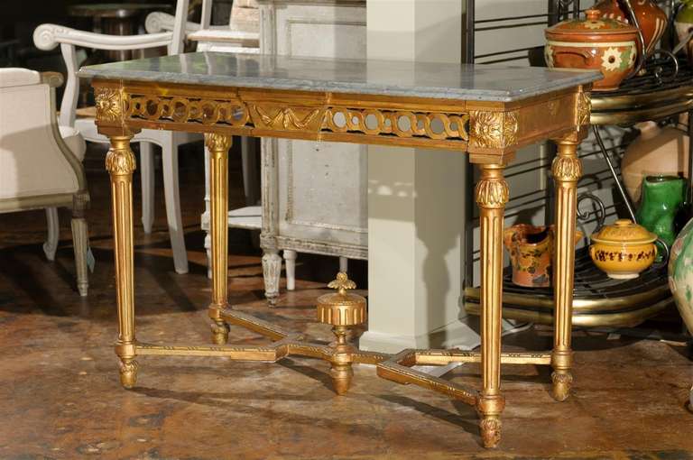 Early 19th century carved giltwood and gesso side table with a grey marble top and molded edges with a pierced guilloche frieze centered by a molded base with acorn shaped feet.