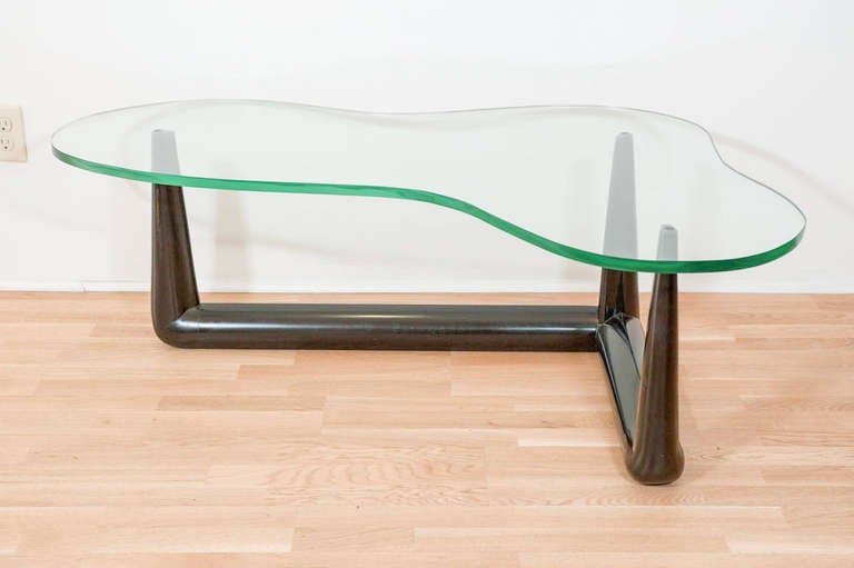 An elegant and timeless wood coffee table with thick glass top by iconic furniture designer T.H Robsjohn-Gibbings.