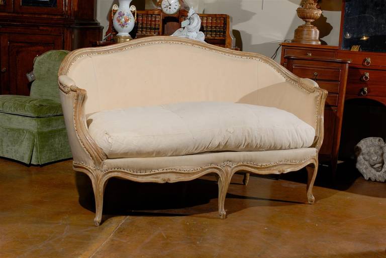 Early 19th century Louis XV style giltwood upholstered settee, the back en corbeille surmounting a conforming seat and raised on five cabriole legs.