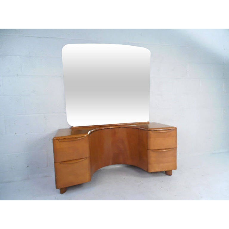 This Heywood Wakefield Mirrored Vanity is the perfect piece to start or complete your Heywood collection. With classic Champagne finish, large mirror, four drawers for storage, and recessed top for vanity seating this vintage piece is a great