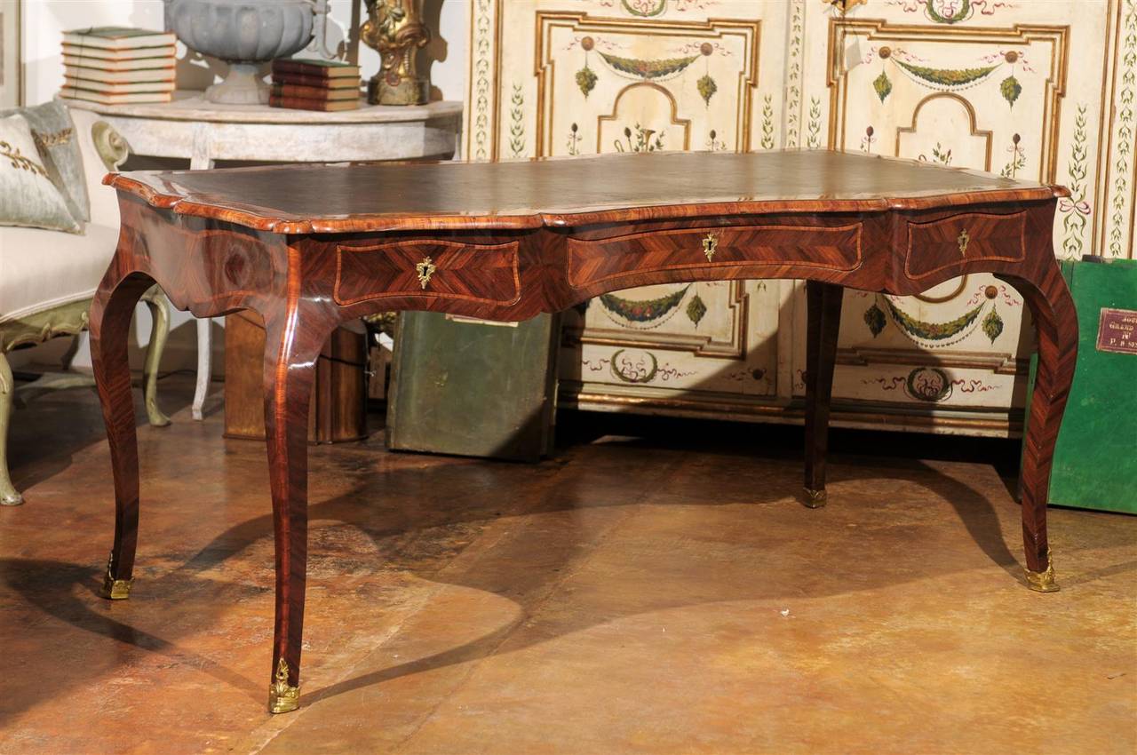 Late 19th century Italian mahogany marquetry inlaid desk, the inset leather scalloped top surmounting three conforming drawers, raised on curved legs terminating in gilt bronze mounted feet, with marquetry inlay throughout.