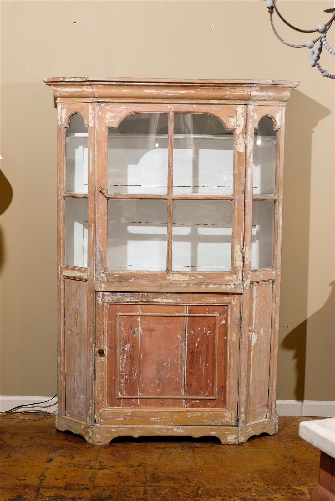 This Dutch curio cabinet from the mid-19th century features a cornice over two pairs of doors placed above each other. The piece is visually separated into two sections: the upper section, made of glass, is the vitrine. The central door, with its