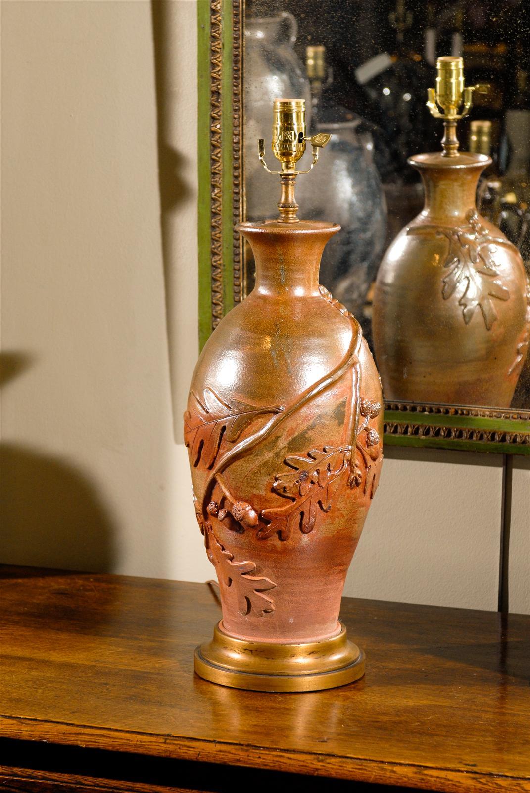 A pair of contemporary South Carolina lustre overglaze ceramic table lamps with applied oak leaves and acorn decor. This pair of vases mounted as lamps features a rich red and orange ombre lustre overglaze adorning a nicely rounded tall shape.