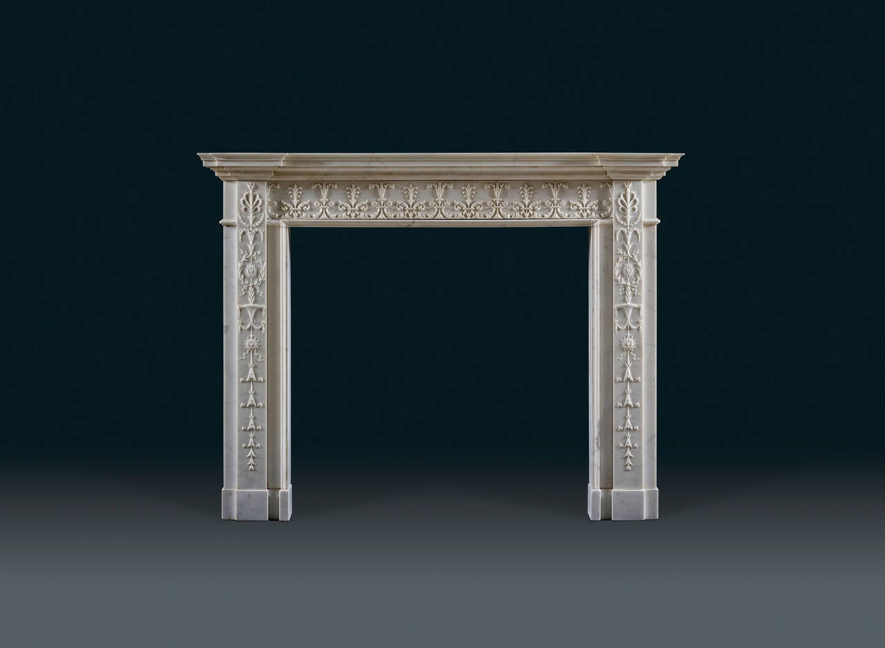 The mantelpiece with delicately moulded edge above a flute-carved band breaking over the jambs the running frieze carved in relief with alternating acanthus and anthemion motifs the stepped jambs each carved with a vertical anthemion capped panel
