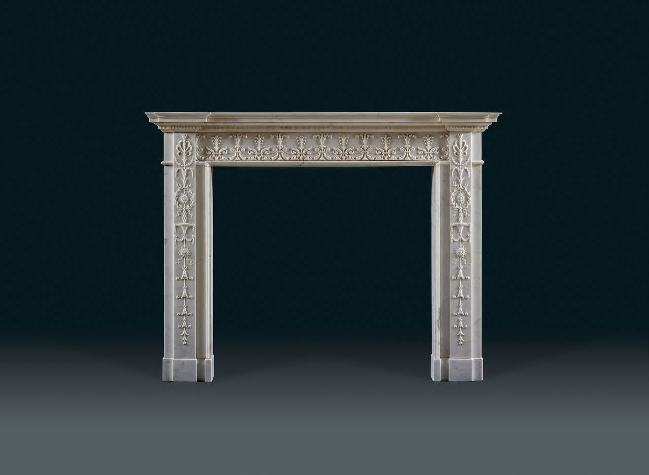 The mantelpiece with delicately moulded edge above a flute-carved band breaking over the jambs the running frieze carved in relief with alternating acanthus and anthemion motifs the stepped jambs each carved with a vertical anthemion capped panel