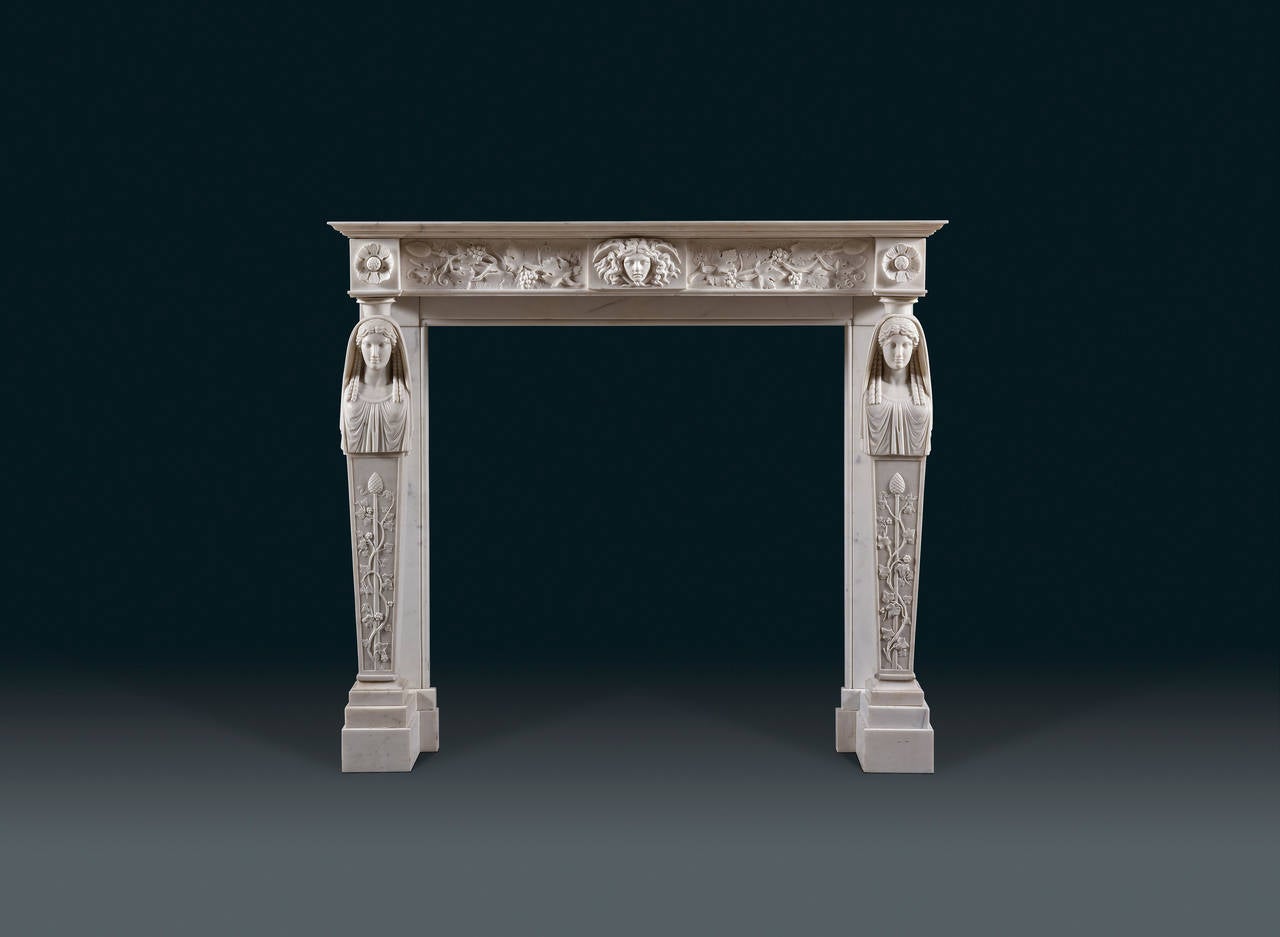 The crisply carved and bold, neoclassical forms of this fireplace are the epitome of fashionable Regency taste. It features a plain shelf above a frieze filled with scrolling vines and bunches of grapes, suggesting it was originally intended for a