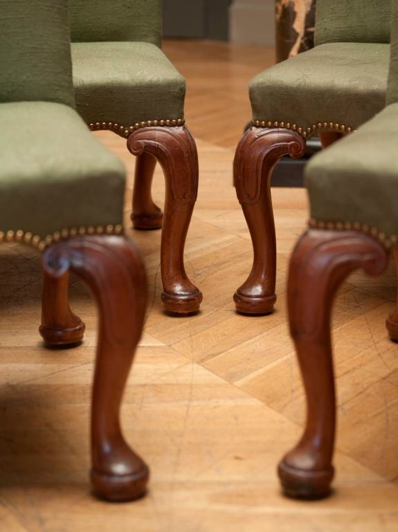 A rare set of four George II mahogany side chairs attributed to Wright and Elwick, circa 1750. Each with serpentine top rails and upholstered serpentine seats, on four cabriole legs, with scrolling panels carved to the knees and recessed castors to