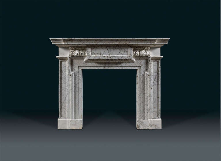 An early 19th century, English chimneypiece in streaked Carrara and Statuary marbles, of strong architectural form with bold and deep mouldings complementing the veins in the marble. The moulded shelf above the frieze which is centered with a large