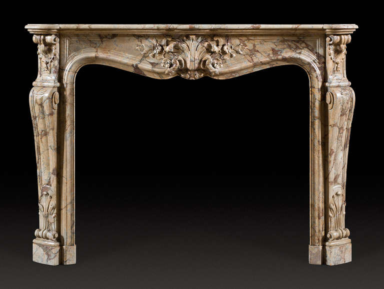 Antique Louis XV style fireplace of exceptional markings and color. With serpentine shaped shelf bowed frieze, decorated with a scallop shell, on spring flowers. The opening with a sensuous elongated s shaped moulding. The canted jambs with scrolled