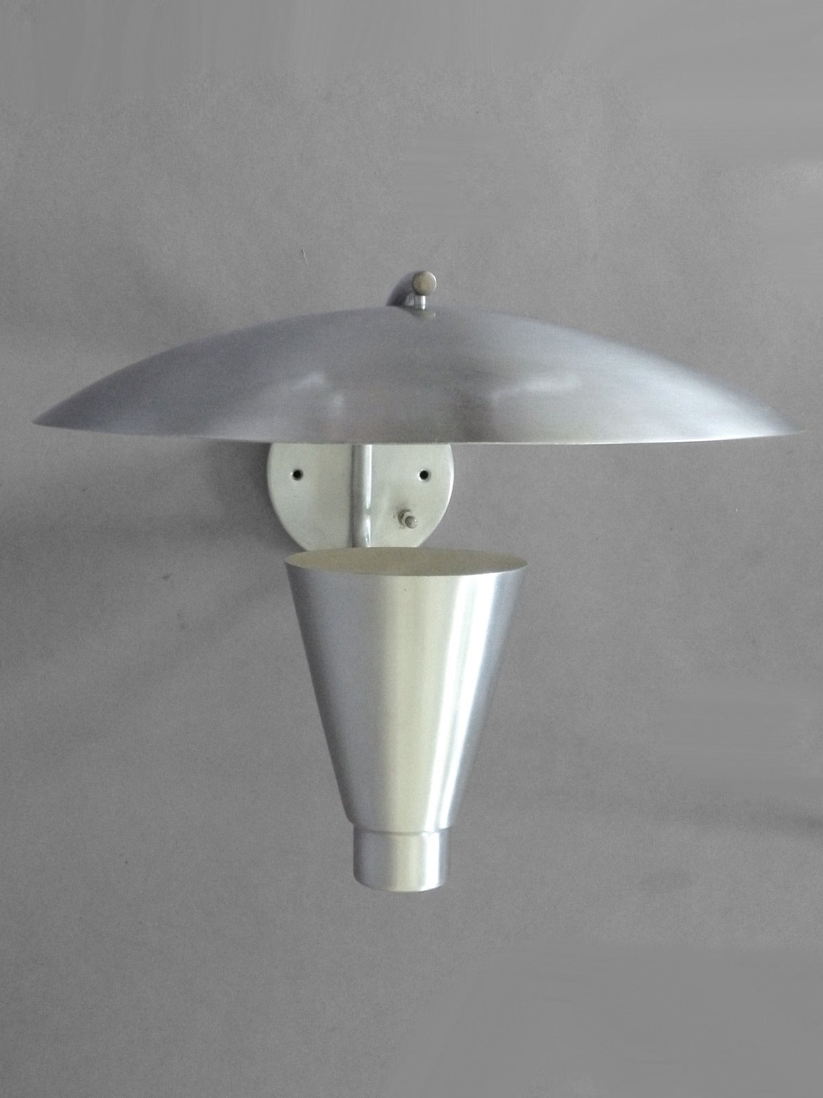 Aluminum cone with deflector wall sconce by Gotham Lighting
Measures: 16” diameter x 18” deep off wall x 14” tall.