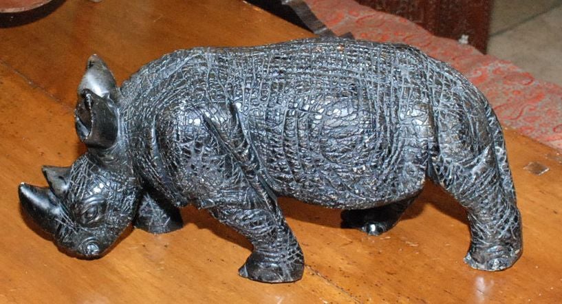 A WHIMSICAL CARVED STONE (VERY HEAVY) RHINO SCULPTURE WITH BRONZE PATINA FINISH.