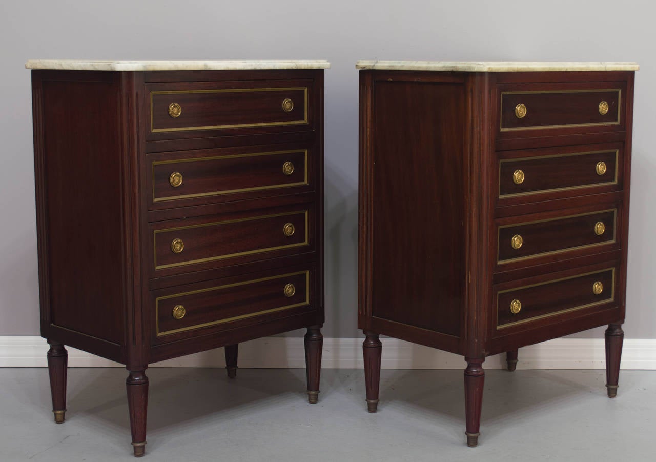A good pair of solid mahogany chests with brass trim and pulls topped with white marble, four dovetailed drawers.