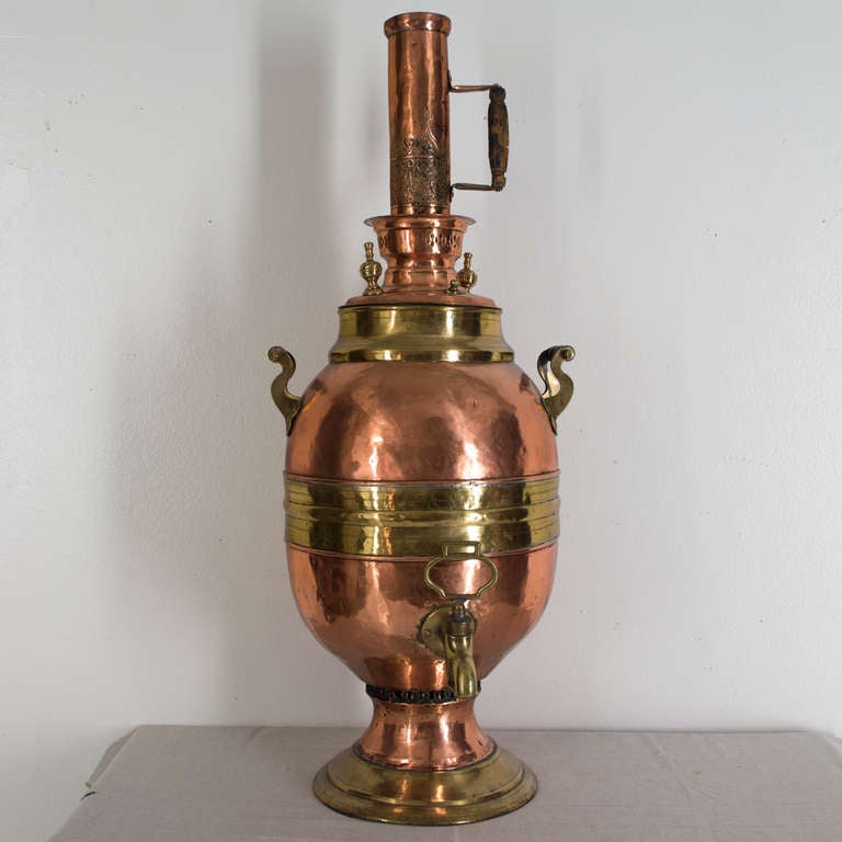 A magnificent 19th c. samovar from a restaurant in Paris. Made of hammered copper and brass with a large brass tap and tall chimney with turned wood handle. This large barrel shaped urn was used for keeping hot water.  A collector's item, it is also