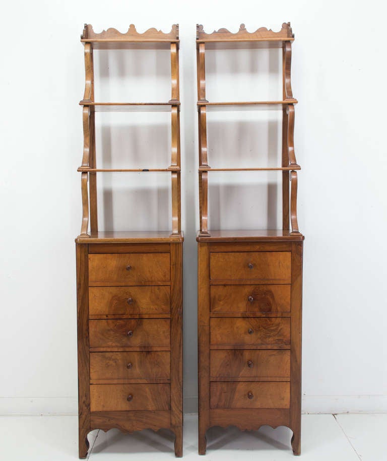 A pair of etageres having three tiers above five dovetails drawers. Made of solid walnut with veneer on the face of the drawers. Space between each tier is 11.5